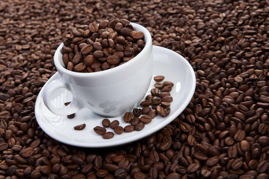 A coffee cup full of coffee beans and sitting on a coffee bean pile