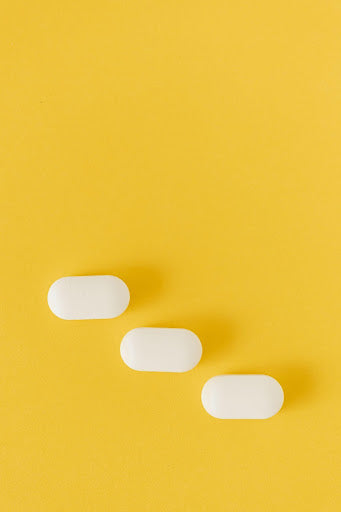 Three L-Theanine capsules on a yellow background.